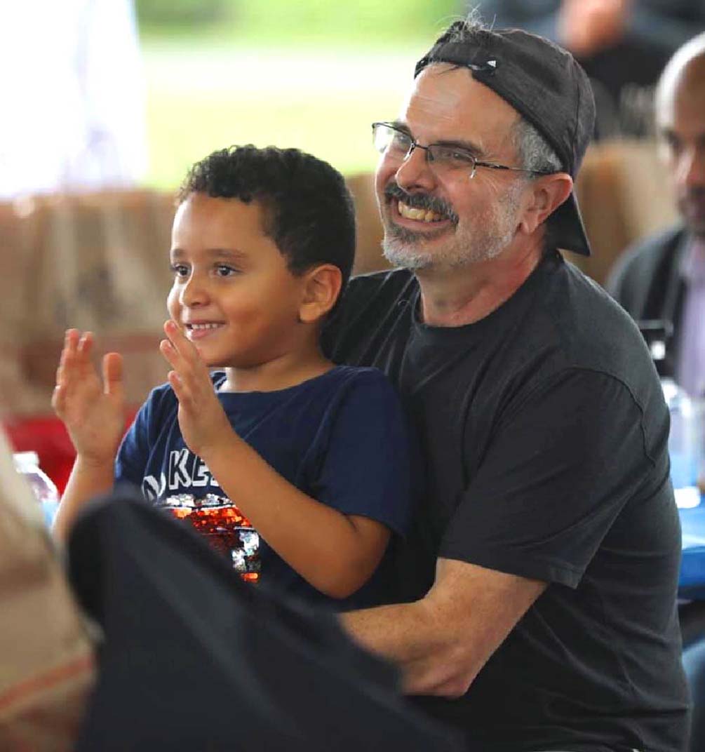 Founder Alain Mentha at a community event with smiling child